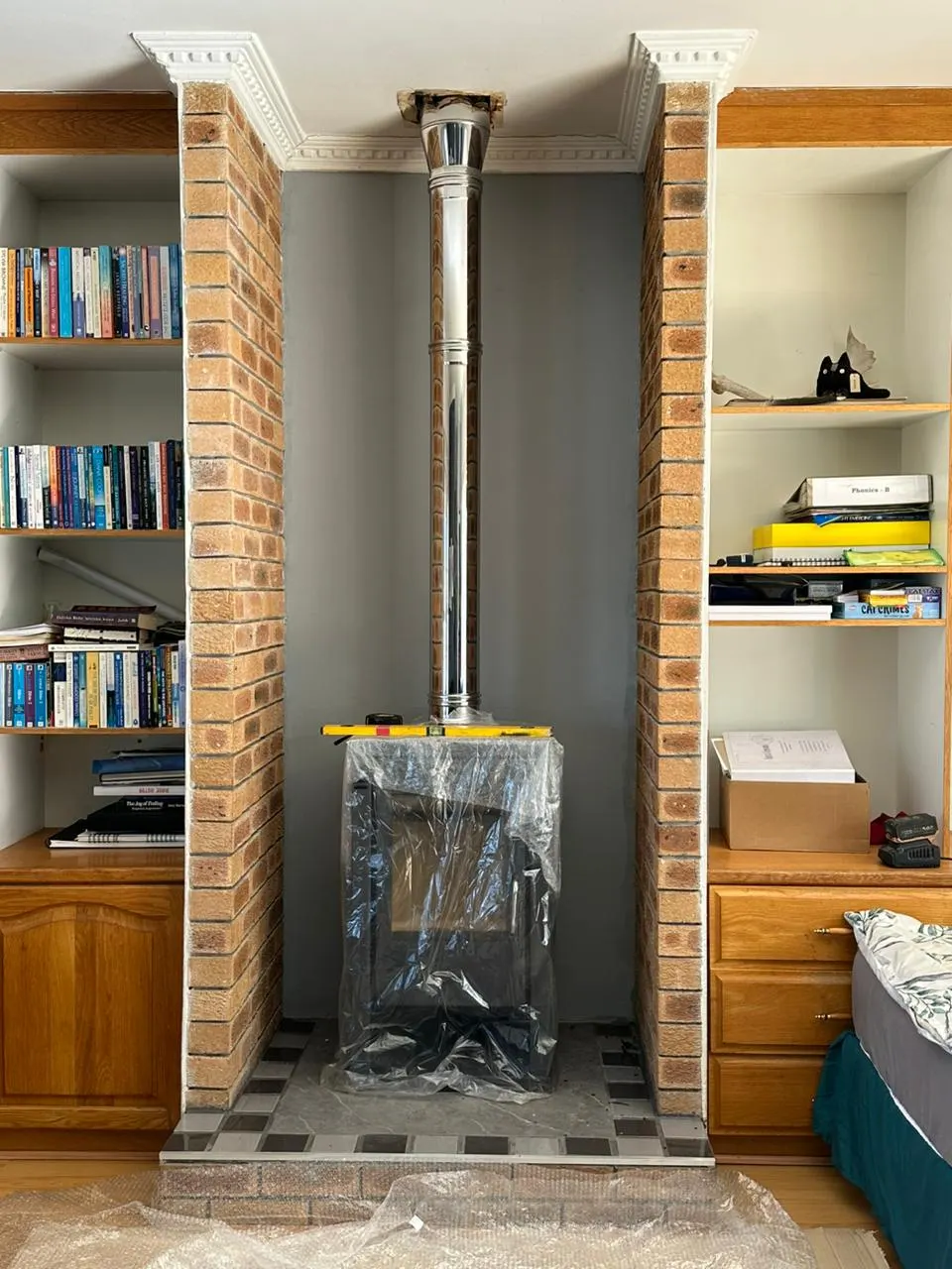 Freestanding fireplace being installed in a brick alcove