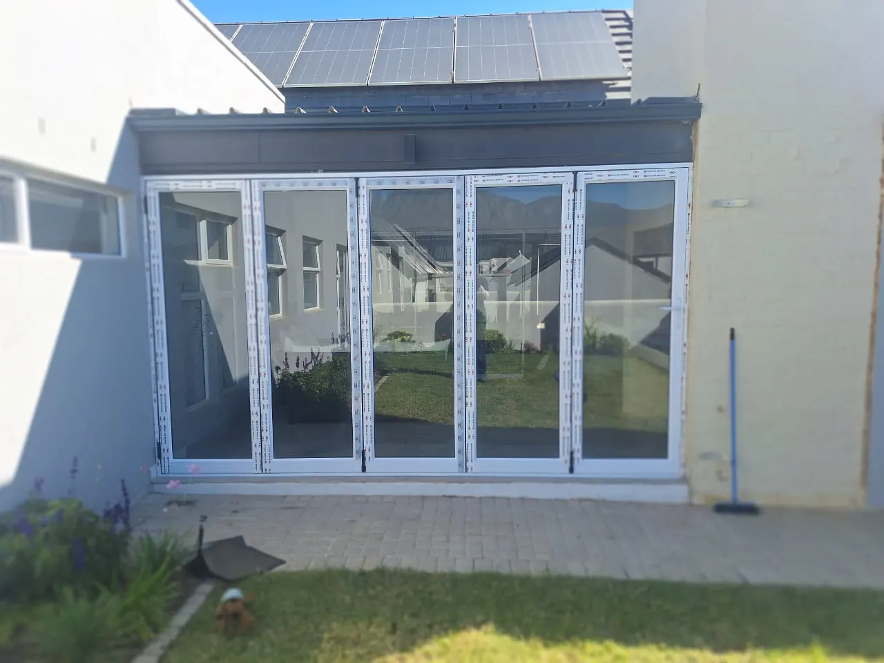 Patio closed in with white folding glass doors, seen from the garden