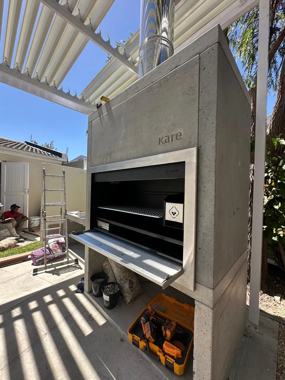 Braai surround with a stainless steel flue rising above the pergola