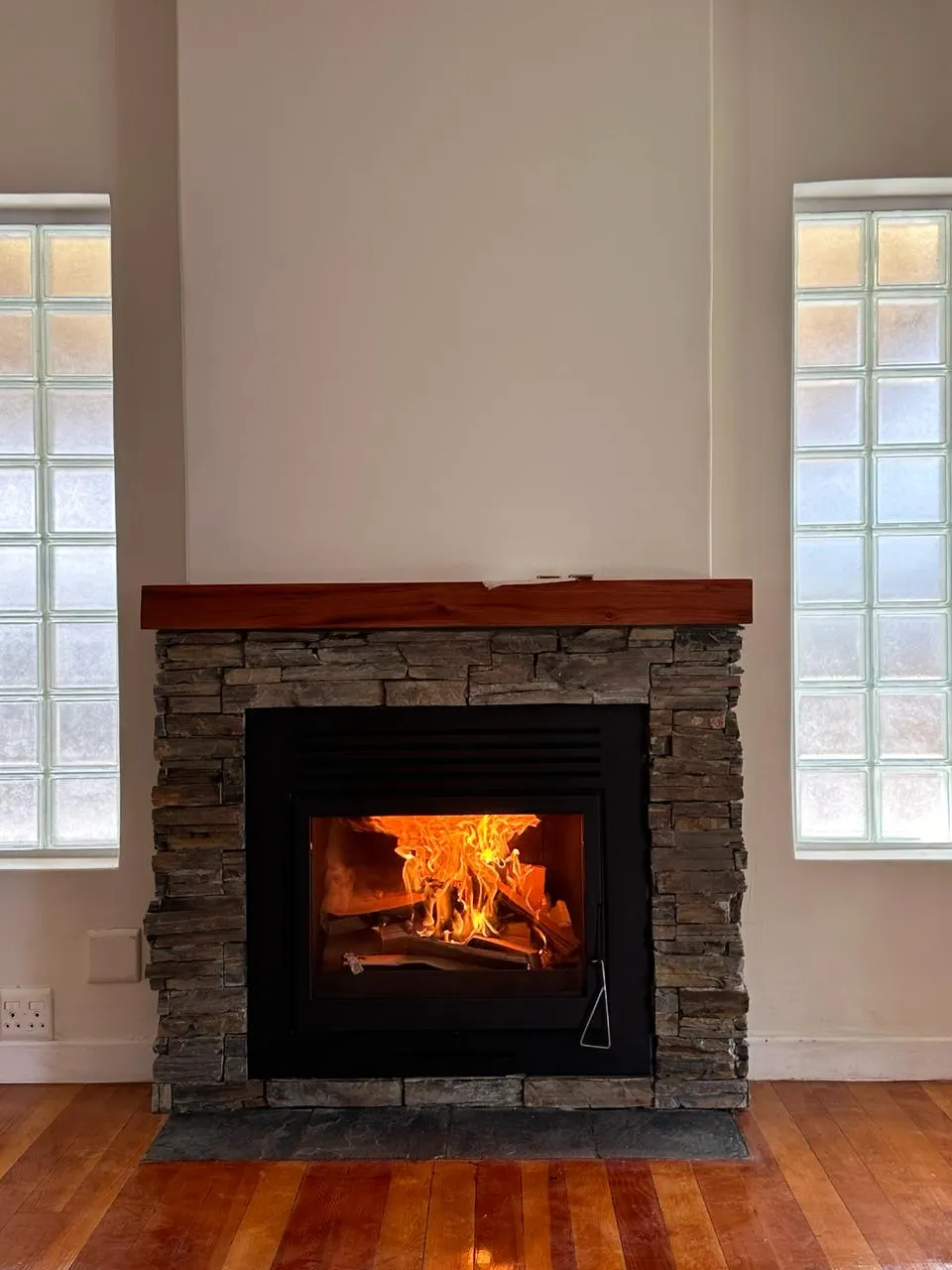 Repaired fireplace with a new insert and a fire burning
