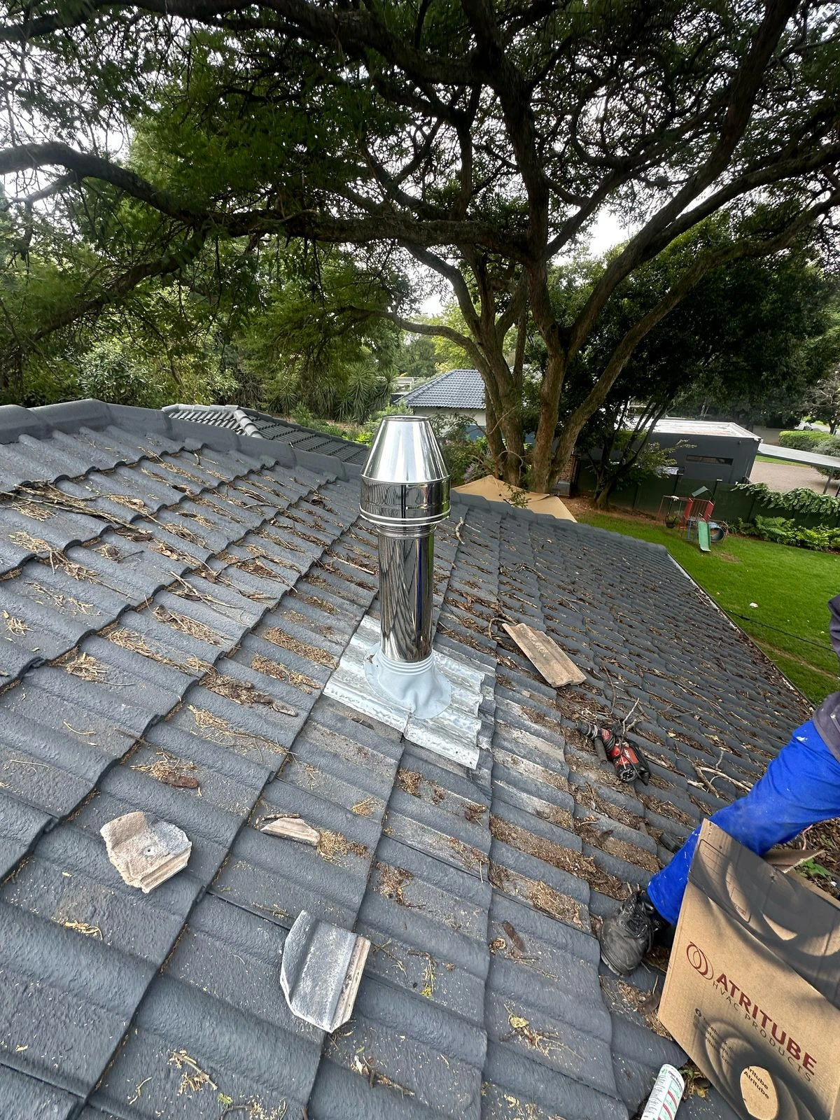 Exterior stainless-steel flue passing through a tiled roof