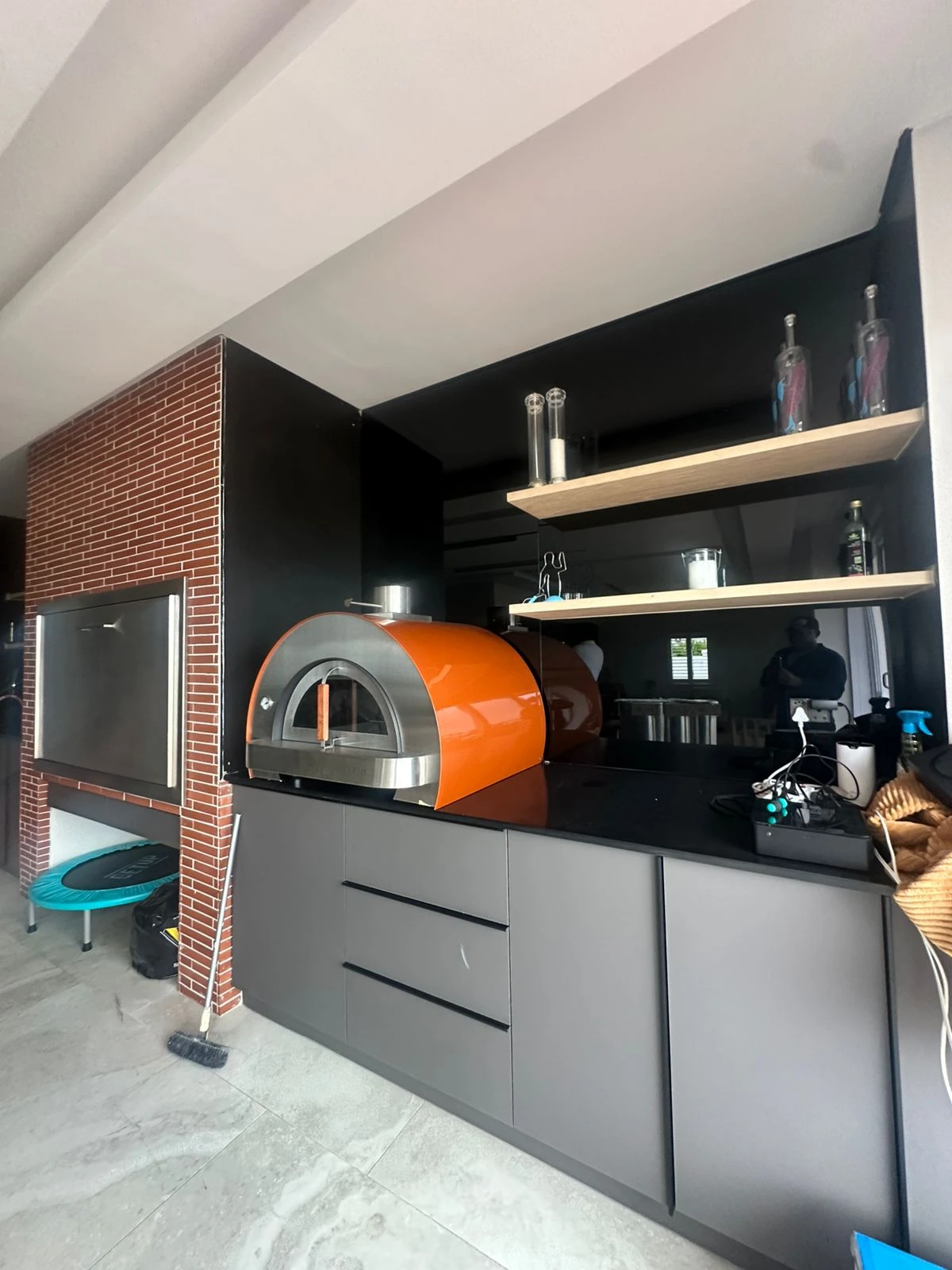 Pizza oven fitted beside a built-in braai with storage cabinets