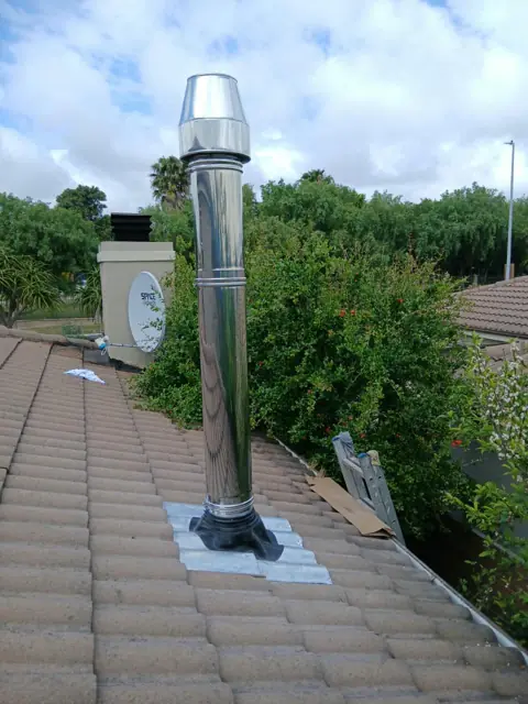 Fireplace flue and cowl installed on a tiled roof, Durbanville