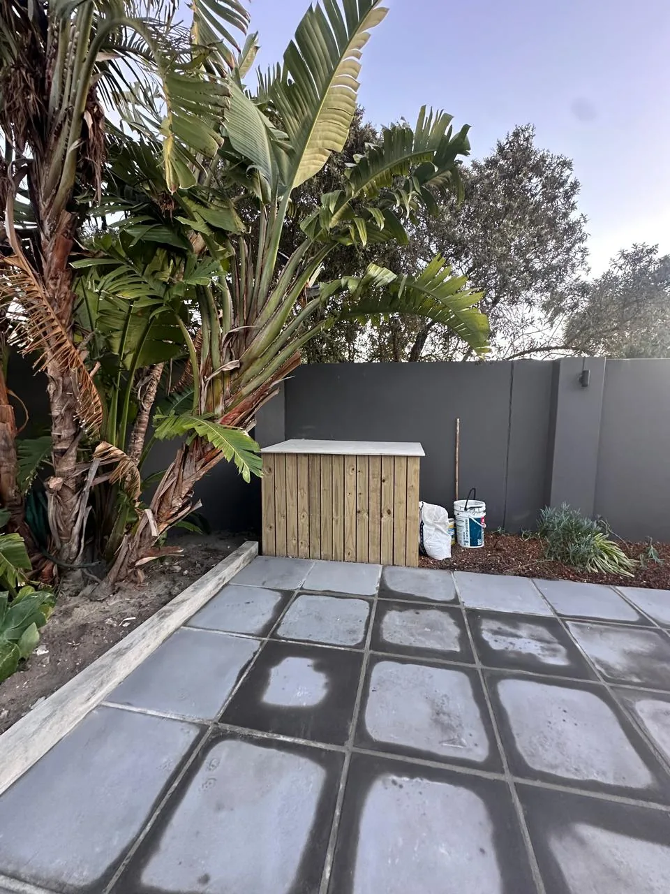 Grey paving slabs laid around a timber garden storage box