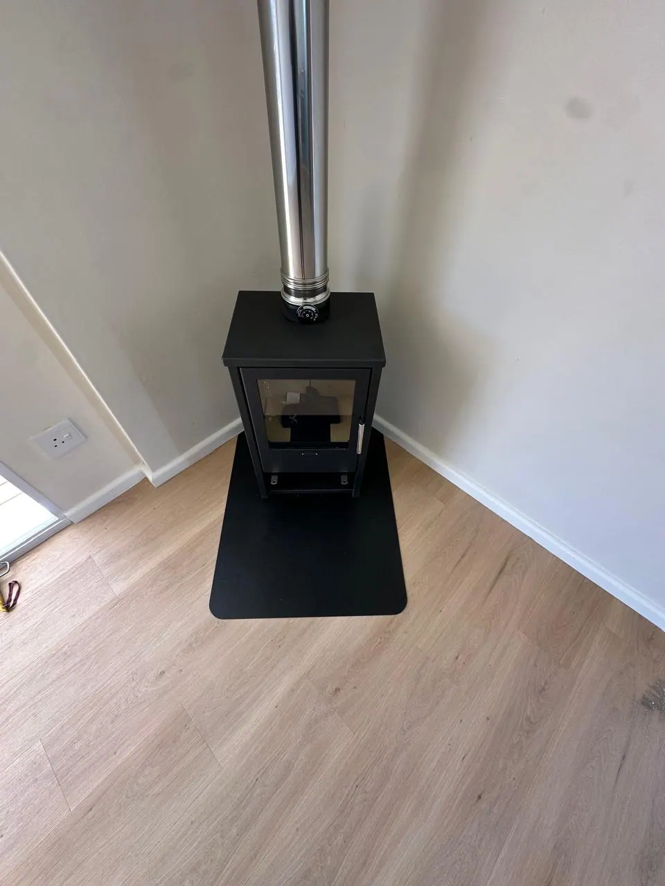 Freestanding fireplace and polished flue on a black hearth pad