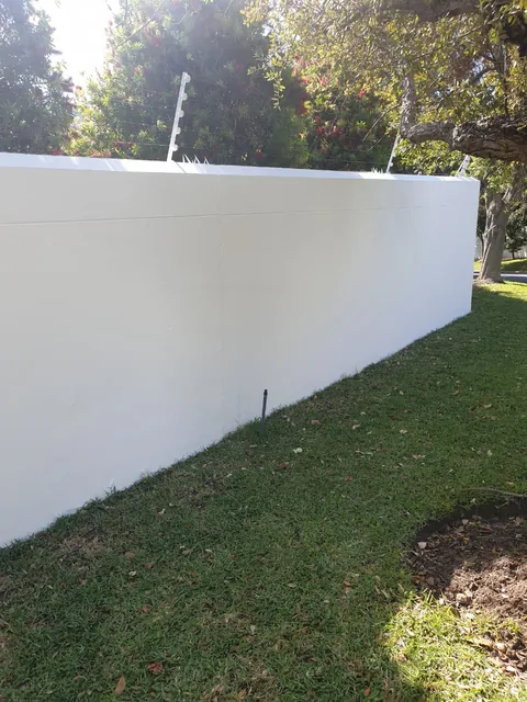 Corner of a freshly painted white boundary wall with an electric fence in Hout Bay