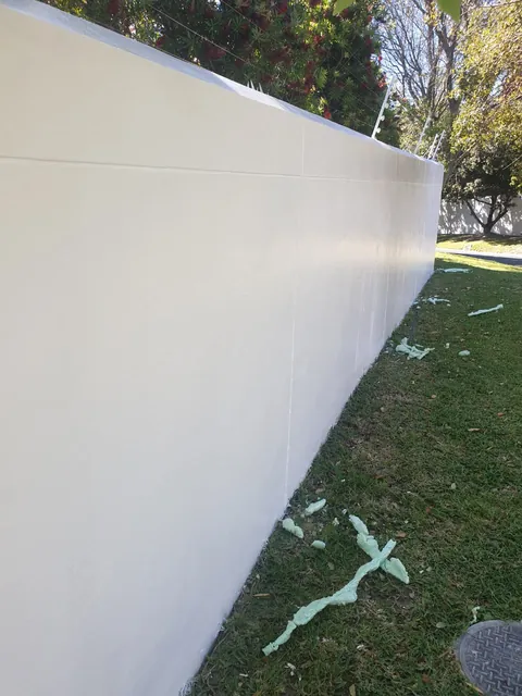 Long boundary wall freshly painted white beside a lawn in Hout Bay
