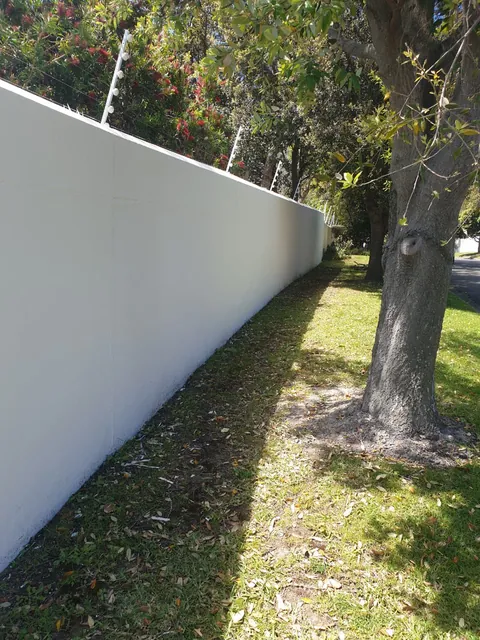 White painted boundary wall under trees in Hout Bay