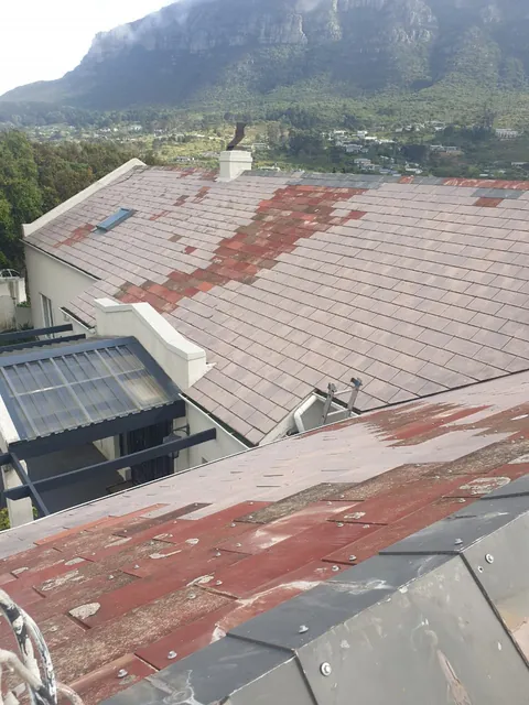 Weathered red roof tiles with faded patches in Hout Bay before painting