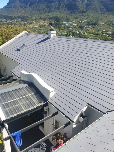 Finished grey painted roof with a skylight and the Hout Bay mountains behind