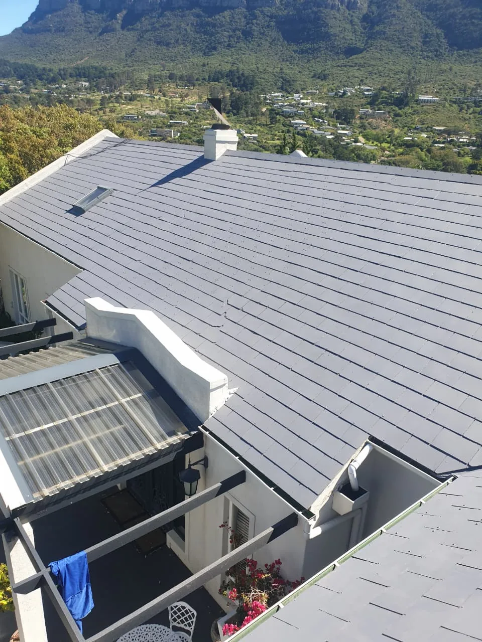 Finished grey painted roof with a skylight and the Hout Bay mountains behind
