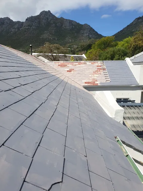 Roof tiles part way through painting in Hout Bay, new grey coat beside faded red tiles